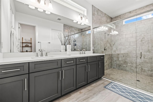 full bathroom featuring double vanity, a shower stall, visible vents, and a sink