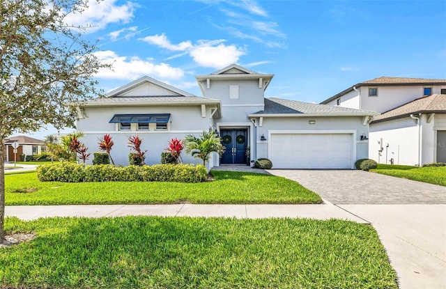 view of front facade with decorative driveway, an attached garage, stucco siding, and a front yard