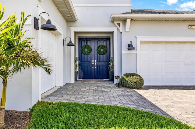 entrance to property with an attached garage and stucco siding