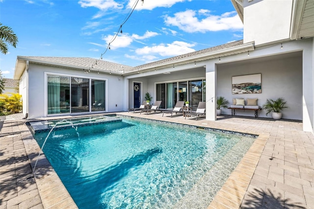 rear view of house featuring stucco siding, a pool with connected hot tub, and a patio