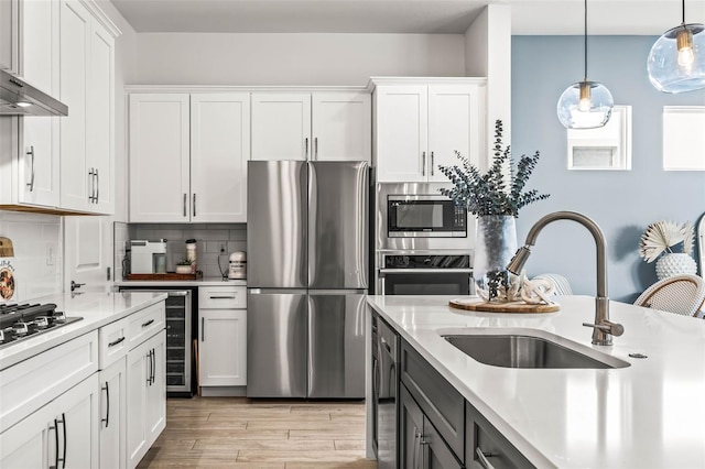 kitchen with stainless steel appliances, light countertops, backsplash, a sink, and beverage cooler