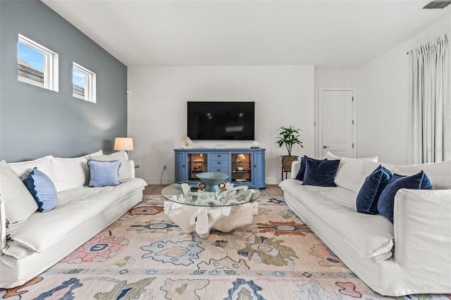 living room with light wood finished floors, visible vents, and baseboards