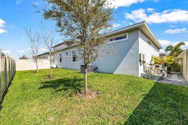 back of house featuring a lawn, a patio, a fenced backyard, central AC, and stucco siding