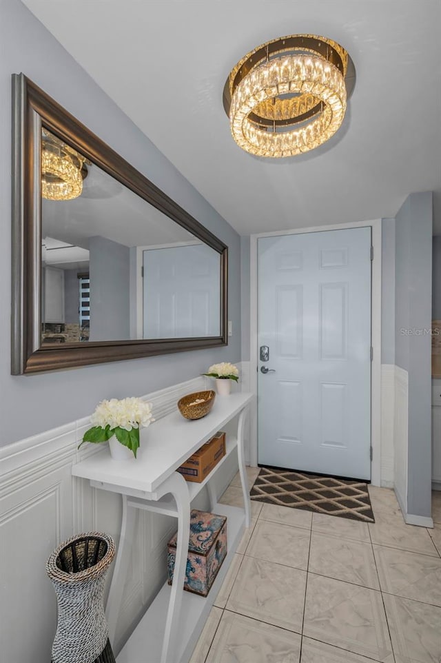 entryway featuring an inviting chandelier and a wainscoted wall