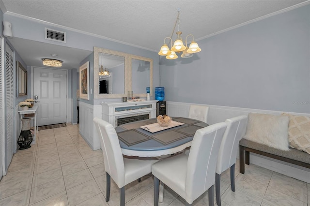 dining area with wainscoting, visible vents, a textured ceiling, and ornamental molding