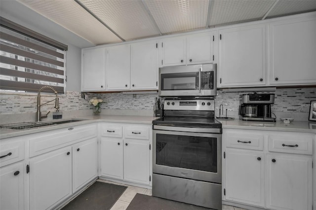 kitchen with stainless steel appliances, light countertops, white cabinetry, and a sink