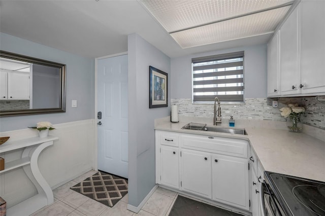 interior space with tile patterned flooring, decorative backsplash, a sink, and wainscoting