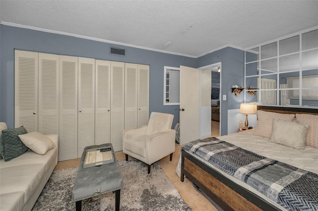 bedroom with crown molding, a closet, visible vents, carpet flooring, and a textured ceiling