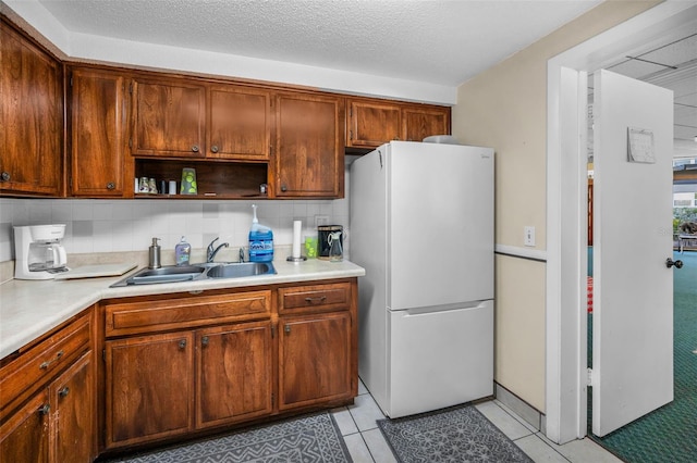 kitchen featuring open shelves, light countertops, freestanding refrigerator, light tile patterned flooring, and a sink