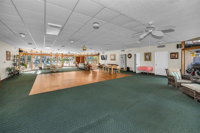 workout area featuring a paneled ceiling, carpet flooring, visible vents, and a ceiling fan