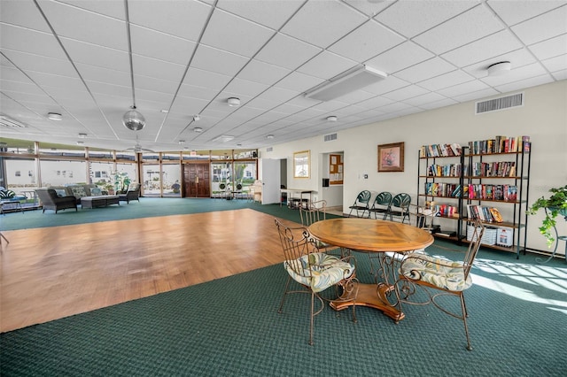 dining area featuring visible vents, a drop ceiling, and wood finished floors