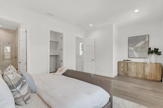 bedroom featuring visible vents, baseboards, wood finished floors, a spacious closet, and recessed lighting