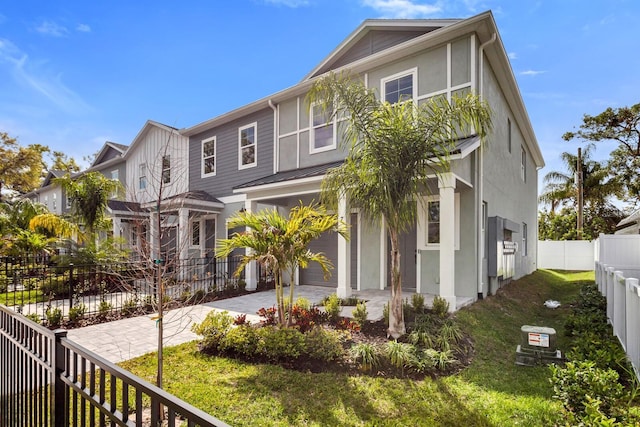 view of front of house featuring a fenced backyard, a garage, decorative driveway, stucco siding, and a front yard