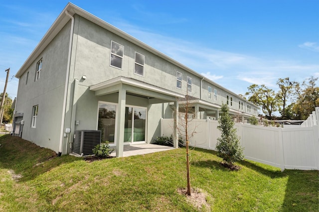 rear view of property with stucco siding, fence, a lawn, and central air condition unit