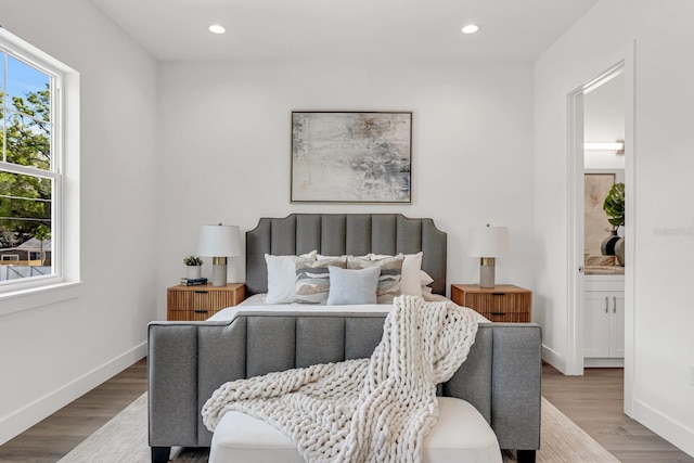 bedroom with connected bathroom, baseboards, wood finished floors, and recessed lighting