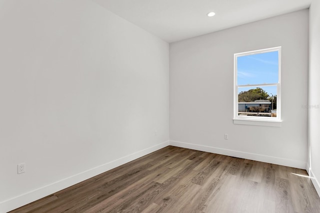 empty room with recessed lighting, wood finished floors, and baseboards