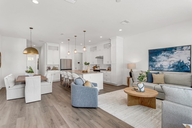 living area with visible vents, wood finished floors, and recessed lighting