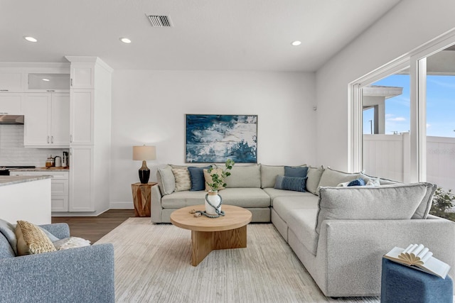 living area with light wood-style flooring, visible vents, and recessed lighting