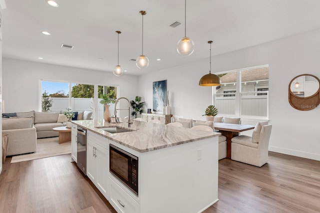 kitchen featuring visible vents, open floor plan, a sink, black microwave, and dishwasher