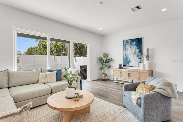 living area with recessed lighting, visible vents, baseboards, and wood finished floors