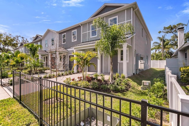 view of front of house with an attached garage, fence, decorative driveway, a residential view, and stucco siding