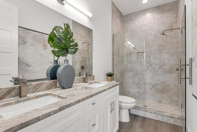 full bath featuring wood finished floors, a stall shower, a sink, and toilet