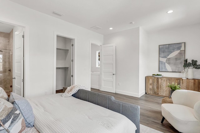 bedroom featuring baseboards, connected bathroom, wood finished floors, a spacious closet, and recessed lighting