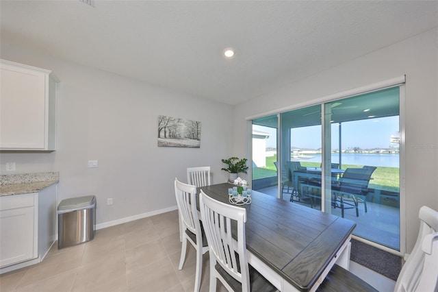 dining area featuring a water view, recessed lighting, baseboards, and light tile patterned flooring