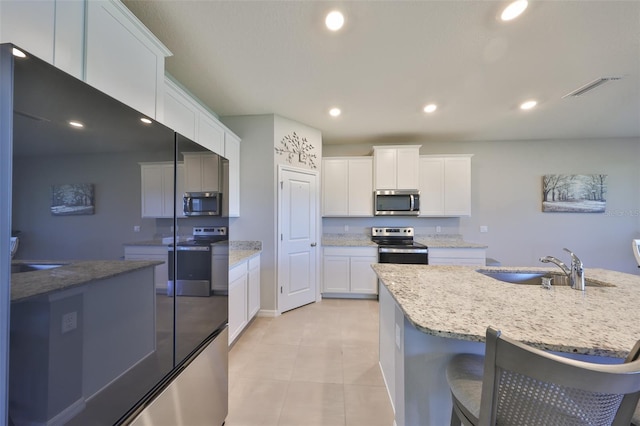 kitchen with appliances with stainless steel finishes, recessed lighting, white cabinets, and visible vents