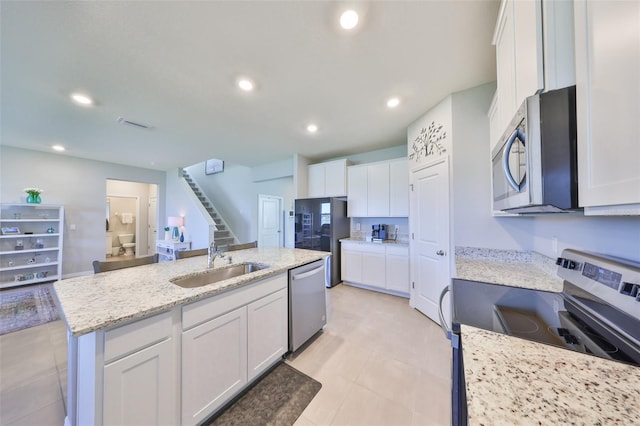 kitchen with white cabinets, appliances with stainless steel finishes, a kitchen island with sink, a sink, and recessed lighting