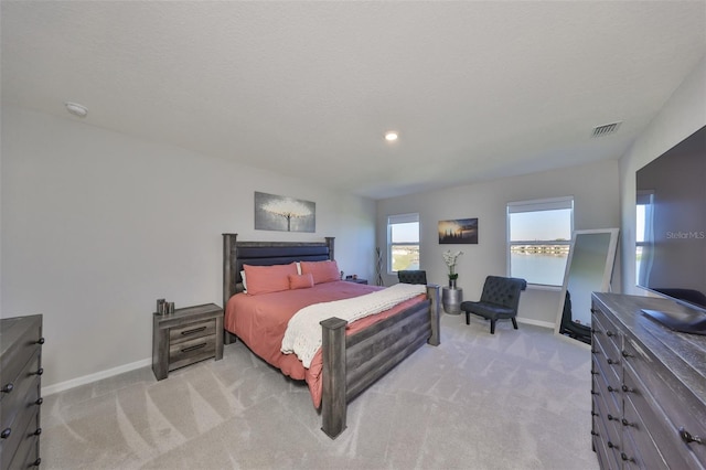 bedroom featuring light carpet, a textured ceiling, visible vents, and baseboards