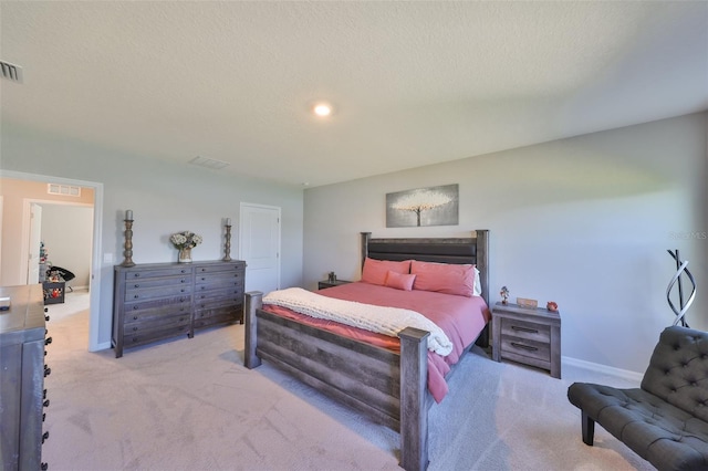 carpeted bedroom with visible vents, a textured ceiling, and baseboards