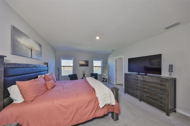 bedroom with a textured ceiling, carpet floors, visible vents, and baseboards