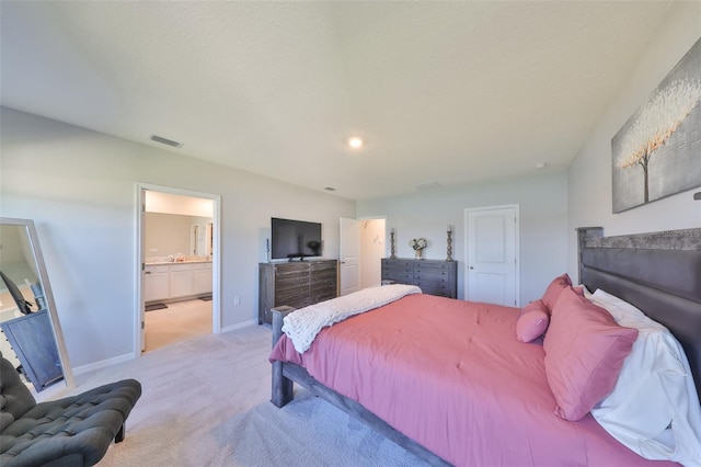 bedroom with light carpet, ensuite bathroom, visible vents, and baseboards