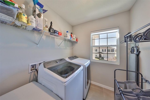 laundry room with laundry area, light tile patterned flooring, washing machine and dryer, and baseboards