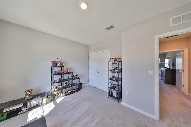 miscellaneous room with visible vents, light carpet, and baseboards