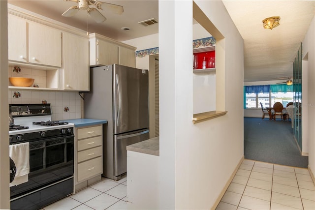 kitchen with ceiling fan, light tile patterned flooring, freestanding refrigerator, open shelves, and gas range