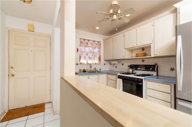 kitchen featuring freestanding refrigerator, backsplash, a sink, and gas stove