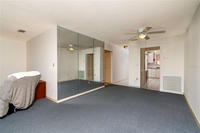 spare room with a textured ceiling, carpet, visible vents, and a ceiling fan