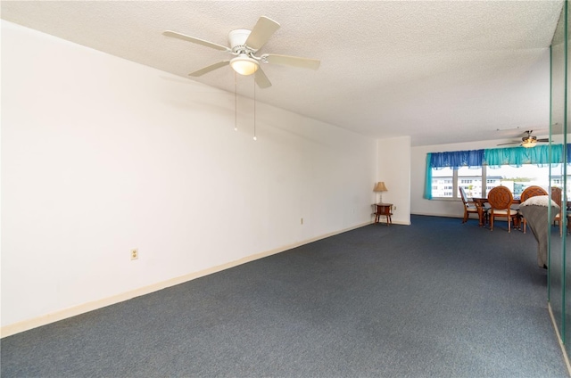 empty room featuring ceiling fan, dark colored carpet, and a textured ceiling