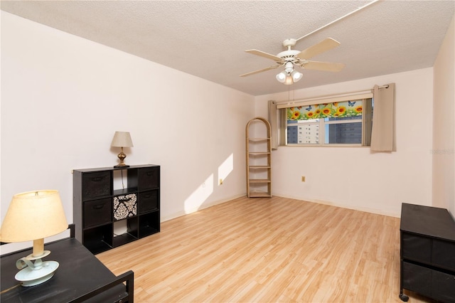 sitting room featuring a textured ceiling, ceiling fan, and wood finished floors