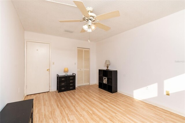 interior space featuring visible vents, a textured ceiling, wood finished floors, and a ceiling fan