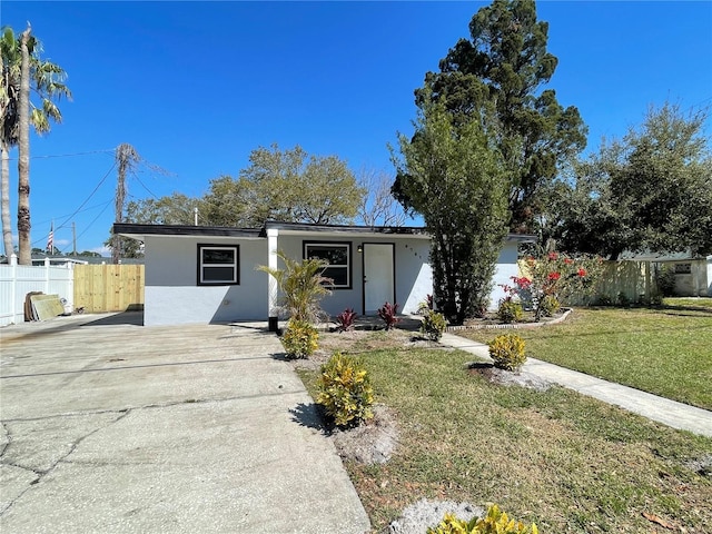 ranch-style house featuring fence, a front lawn, and stucco siding