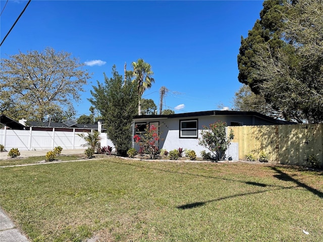 ranch-style home with a front lawn, fence, and stucco siding