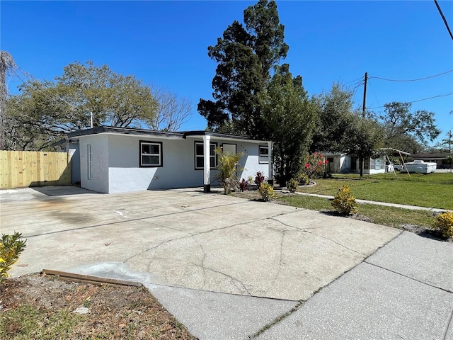 view of front of property with a front yard, fence, driveway, and stucco siding