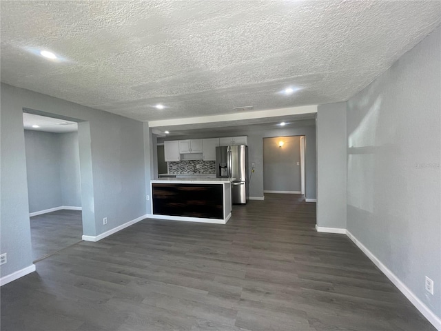 kitchen featuring dark wood-style floors, light countertops, decorative backsplash, open floor plan, and stainless steel fridge