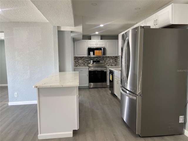 kitchen featuring baseboards, stainless steel appliances, wood finished floors, and decorative backsplash