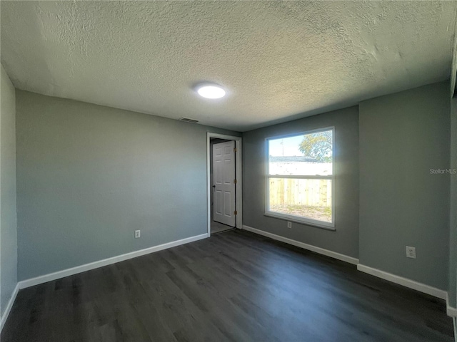 unfurnished room with baseboards, a textured ceiling, visible vents, and dark wood-style flooring