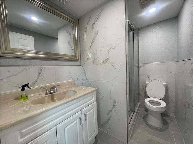 full bath with tile walls, visible vents, toilet, a stall shower, and vanity