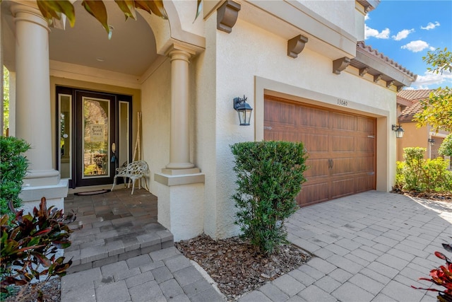 entrance to property featuring decorative driveway, a tile roof, and stucco siding